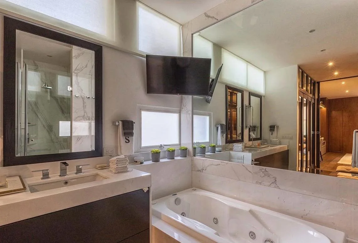 Baño de suite con lavabos y acabados de piedra